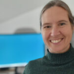 Porträtfoto Henriette Schwarzer, mit PC-Monitor im Hintergrund.