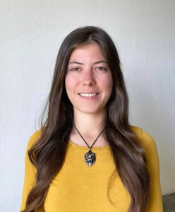 Porträtfoto Anna-Lena Bach, mit langen schwarzen Haaren und gelben T-Shirt lächelt Sie in die Kammera